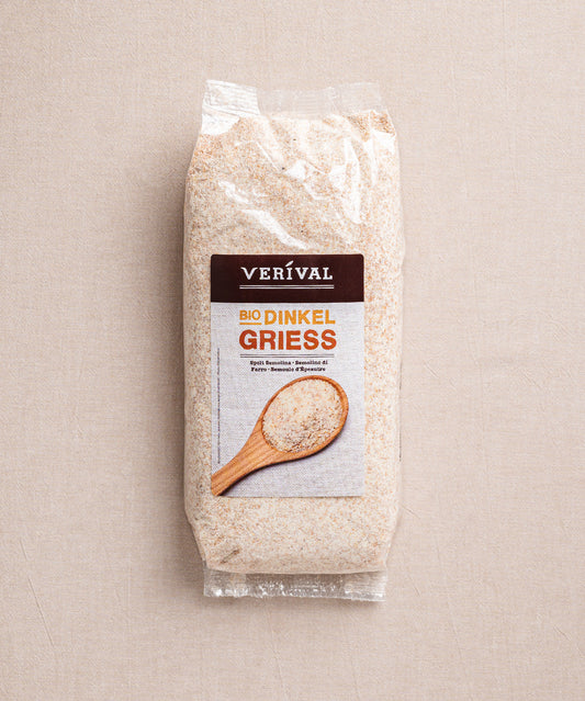 Eine Packung Dinkelgrieß der Verival Bio GmbH zeigt ein Etikett mit einem Holzlöffel voll Grieß. Die transparente Verpackung offenbart die körnige Textur des Grieß, der reich an Ballaststoffen und Proteinen ist.