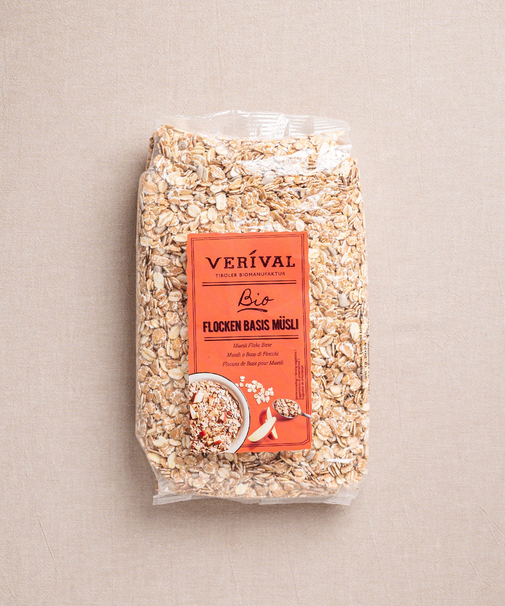 Eine Packung Flocken Basis Müsli von Verival Bio mit orangefarbenem Etikett, auf dem Haferflocken und eine Schüssel Müsli abgebildet sind. Sie ist versiegelt und steht vor einem neutralen Hintergrund.