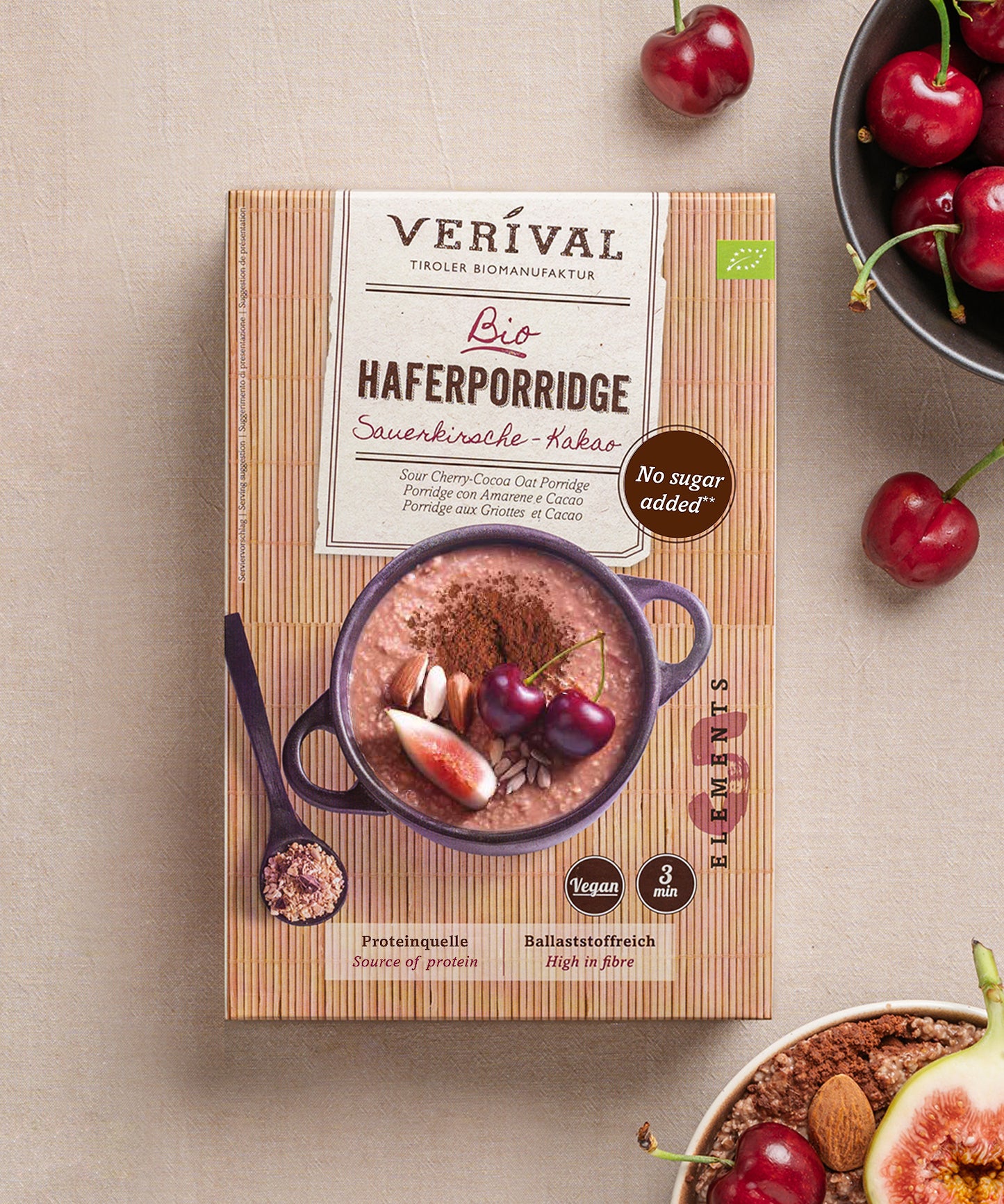 Eine Packung Sauerkirsche-Kakao Haferporridge von Verival Bio steht mit frischen Kirschen und einer Porridge-Bowl auf einem Tisch. Vollgepackt mit Ballaststoffen, kommt dieser vegane Leckerbissen ohne Zuckerzusatz aus, ist in 3 Minuten fertig und entspricht den Prinzipien der TCM-Ernährung.