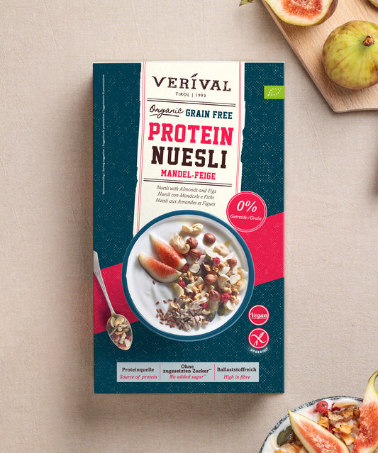 Eine Packung Bio Mandel-Feige Grain Free Protein Nüsli der Verival Bio GmbH, abgebildet neben frischen Feigen und einer Schüssel Müsli mit Joghurt.